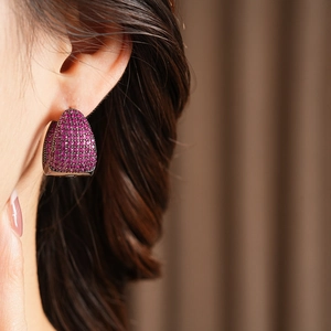 Detailed macro view of rose red cubic zirconia stones pavé-set on a C-shaped earring