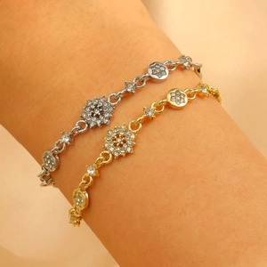 Close-up detail of silver and gold crystal flower bracelets on wrist with sparkling rhinestones