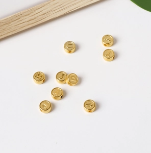 Flat lay of gold acrylic letter beads for DIY jewelry making on white background