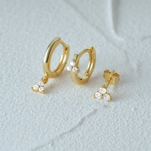 Macro shot of S925 sterling silver gold earrings with sparkling white zircon settings