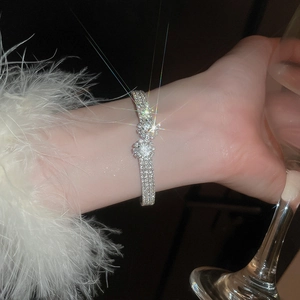 Detail of silver sparkling crystal flower bracelet worn with elegant feather cuff