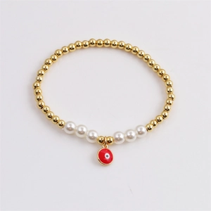 Bracelet doré avec pendentif œil maléfique rouge et perles blanches sur blanc