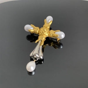 Macro shot of cross pendant with gold and silver metal textures and inlaid white pearls