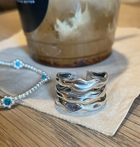 Close-up of a silver multi-layered wave ring and beaded flower bracelet on a table