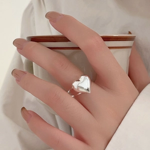 Lifestyle shot of a 925 silver heart ring worn on hand holding a coffee cup