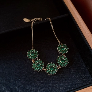 Détail du bracelet plaqué or 18 carats avec fleurs en zircon vert émeraude sur velours noir