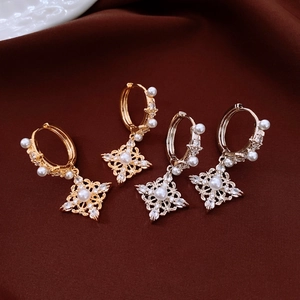 Détail de boucles d'oreilles étoile en or 18 carats avec perles sur tissu bordeaux