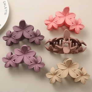 Detailed view of matte flower hair claws in purple, pink, beige, and brown colors