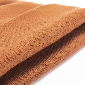 Close-up of caramel knit beanie fabric showing fine stitching and warm texture