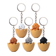 Detail showing five cute 3D cartoon teddy dogs in eggshells on metal keychains