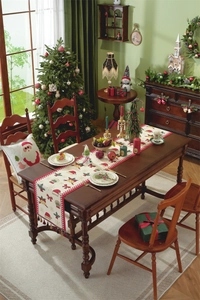 Detail view of beige Christmas table runner with red borders, tassels, and holiday motifs