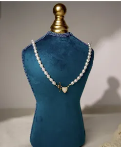 Detail of freshwater pearl necklace with gold heart pendant and toggle clasp on velvet display