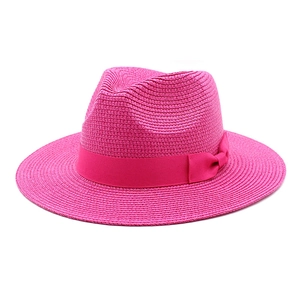Detailed close-up of rose red woven straw sun hat with decorative satin bow ribbon