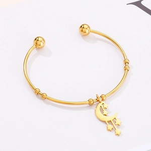 Detail view of a gold-plated stainless steel cuff bracelet with moon and star charms