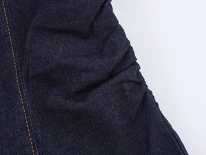 Dettaglio del tessuto denim blu scuro con cuciture a contrasto di alta precisione