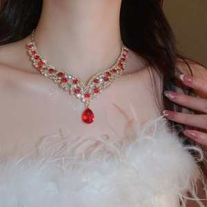 Detail of luxury necklace with gold chain and large pear-shaped red crystal pendant
