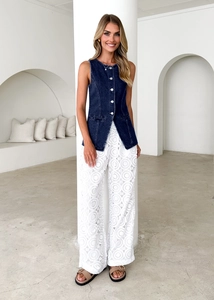 Detail of vintage blue denim vest paired with white floral lace wide leg pants on a model