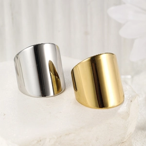 Close-up of minimalist gold and silver wide-band stainless steel rings on stone base