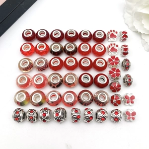 Detailed close-up of red and silver DIY beads with floral, paw, and butterfly patterns