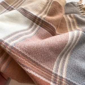 Detail of soft earth-tone plaid scarf with thick fringe and knit texture in macro view