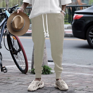 Detail of khaki jogger pants with waffle knit texture and white drawstring on a model