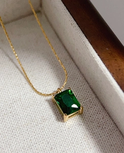 Macro shot of rectangular emerald-cut green zircon pendant with 18k gold-plated chain