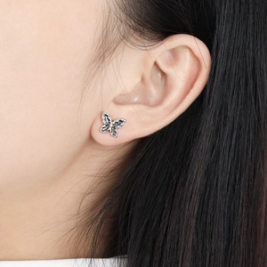 Minimalist black butterfly S925 sterling silver stud earrings on a model’s ear