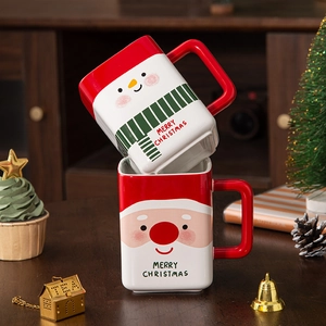 Ceramic Santa and Snowman Christmas coffee mugs with Merry Christmas text on wooden table