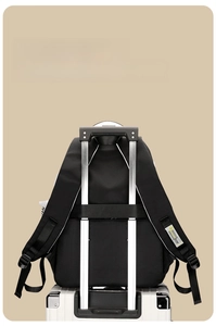 Detailed back view of backpack showing the luggage strap secured to a suitcase handle