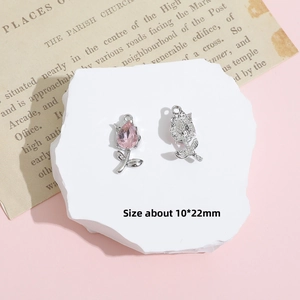 Macro detail of a 10x22mm silver rose charm with pink teardrop crystal on a stone