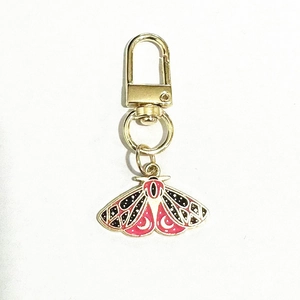 Exquisite gold butterfly keychain with pink and black enamel moth pendant on white base