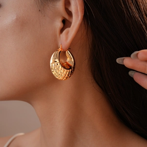 Detail of vintage gold geometric textured hoop earring worn on model for stylish look