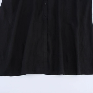 Détails de l'ourlet d'une robe licou noire avec patte de boutonnage et tissu en coton mat