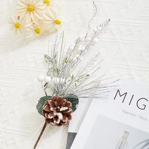 Artificial Christmas stem with snowy pine cones, white berries and pine needles on fabric