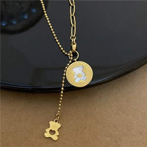 Detailed macro view of golden bear pendant with white shell inlay and asymmetric chain