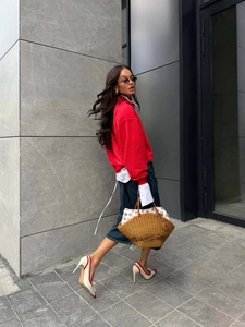 Fashionable red quarter-zip sweatshirt styled with a denim midi skirt and straw tote bag