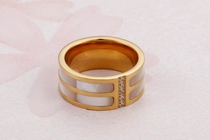 Macro view of gold plated wide band ring with white shell inlay and sparkling crystals