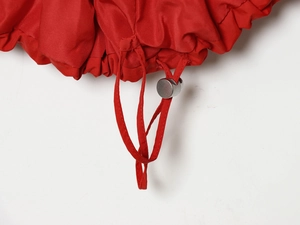 Detailed macro view of red nylon fabric with silver metal drawstring toggle and ribbon