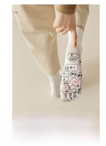 Detailed view of white cotton five-toe massage socks showing reflexology foot map