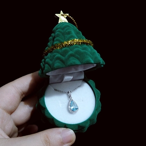 Detail of light blue teardrop pendant necklace in a green Christmas tree jewelry box
