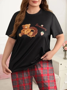 Dettaglio dei pantaloni scozzesi rossi e t-shirt nera con stampa orso pigiama