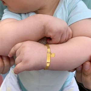 Close-up of golden stainless steel baby mesh bracelet with blank ID tag and heart charm