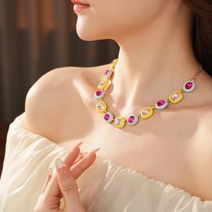 Close-up of vintage gold necklace with pink gems and pastel enamel on a woman's collarbone