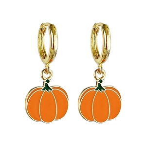 Macro shot of gold hoop earrings featuring orange enamel pumpkin charms with green stems