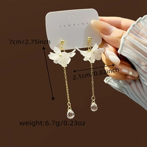 Detail of white flower tassel earrings featuring frosted petals and clear waterdrop charms