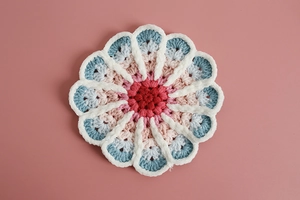 Macro shot of handmade crochet gradient coaster with cotton weave texture on pink background