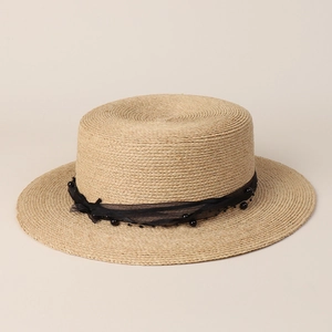 Detailed texture of woven raffia boater hat with black chiffon ribbon and beads