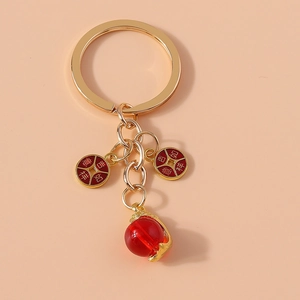 Detail of gold lucky charm keychain with red beads and engraved Chinese characters