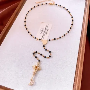 Collier de perles noires vintage avec pendentif clé dorée et détail de pierre brune