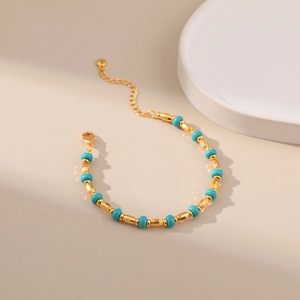 Detailed shot of handmade turquoise beads on a gold metal chain with lobster clasp